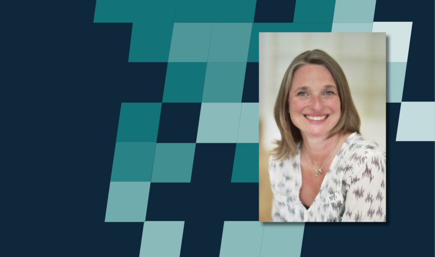 A photo of PIF director Sophie Randall smiling and looking at the camera in front of a dark blue chequered background.