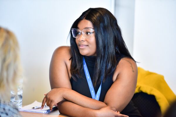 A photo of a woman wearing glasses and a blue lanyard at a PIF networking event.