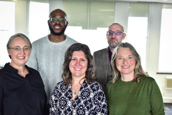 A photograph of the PIF team in front of a wall of windows.